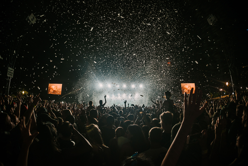 Night concert crowd cheering under falling confetti