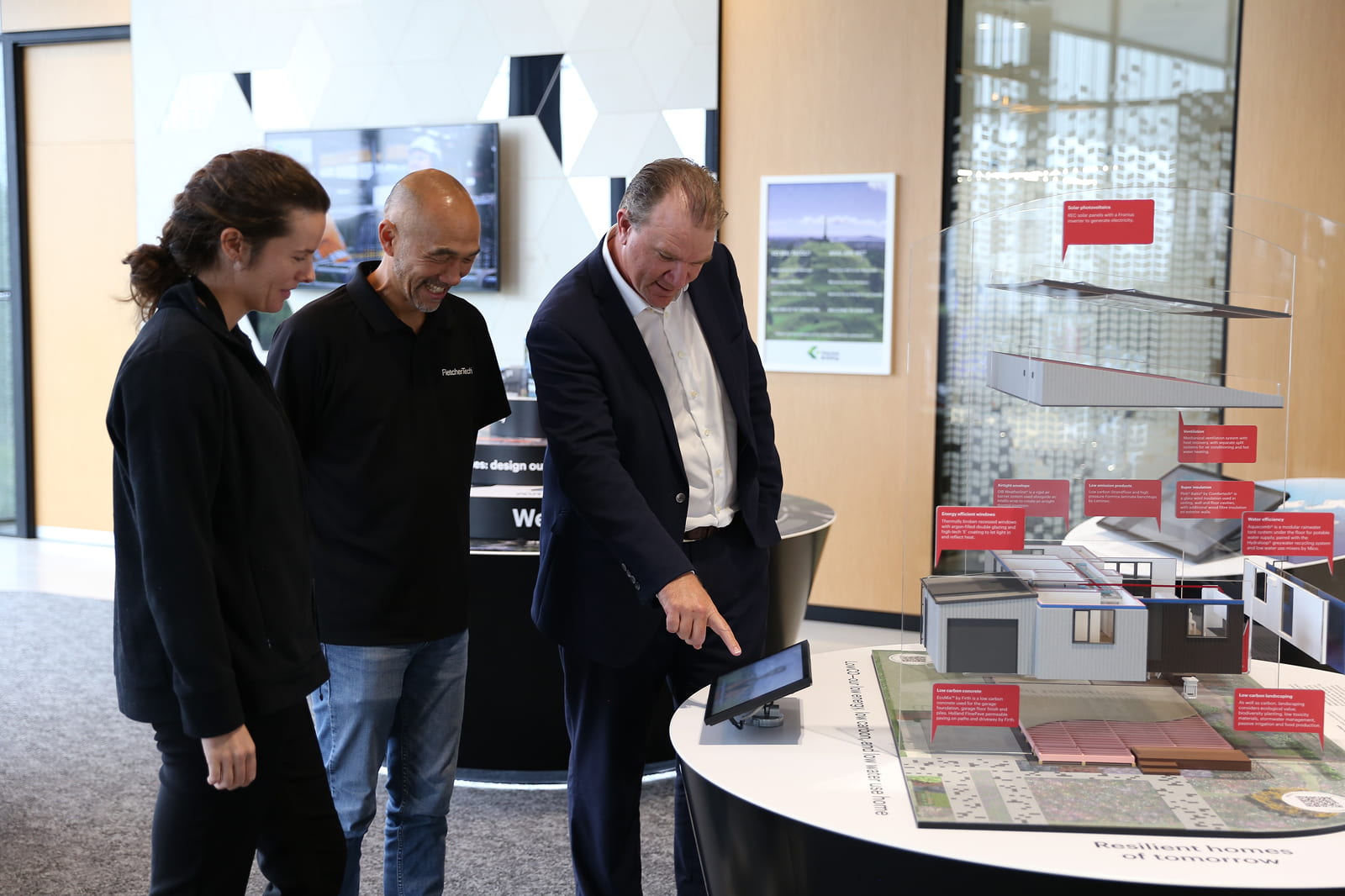 FletcherTech team looking at a tablet screen with a construction model in the background