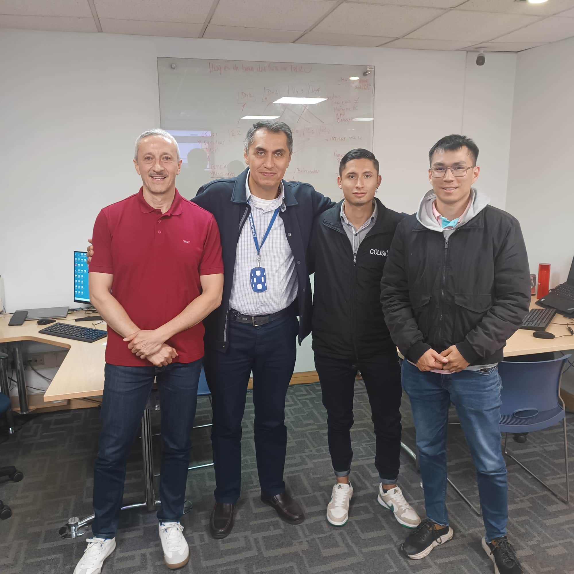 Four smiling men standing together in an office workspace