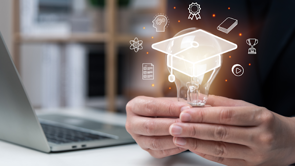 person holding lightbulb with icons surrounding lightbulb and laptop in background