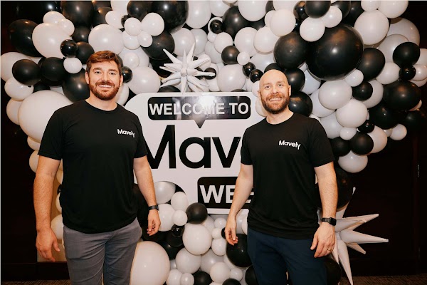 Two men standing in front of black and white balloons