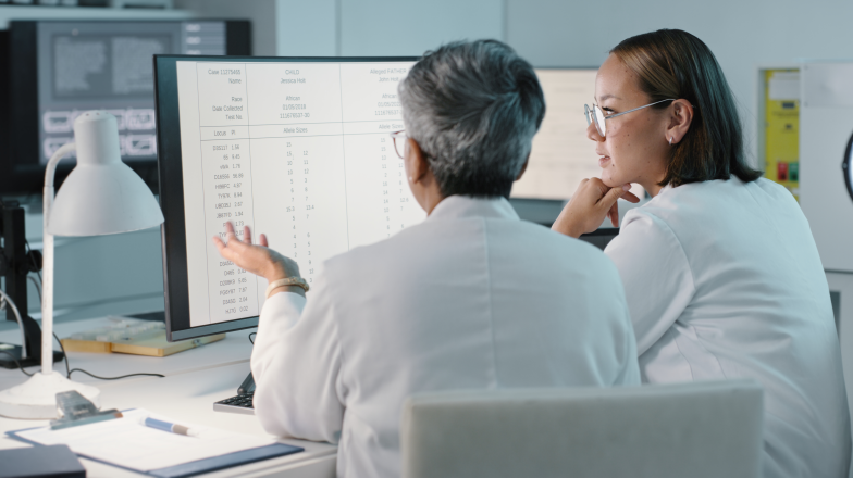 two researchers in lab coats reviewing data