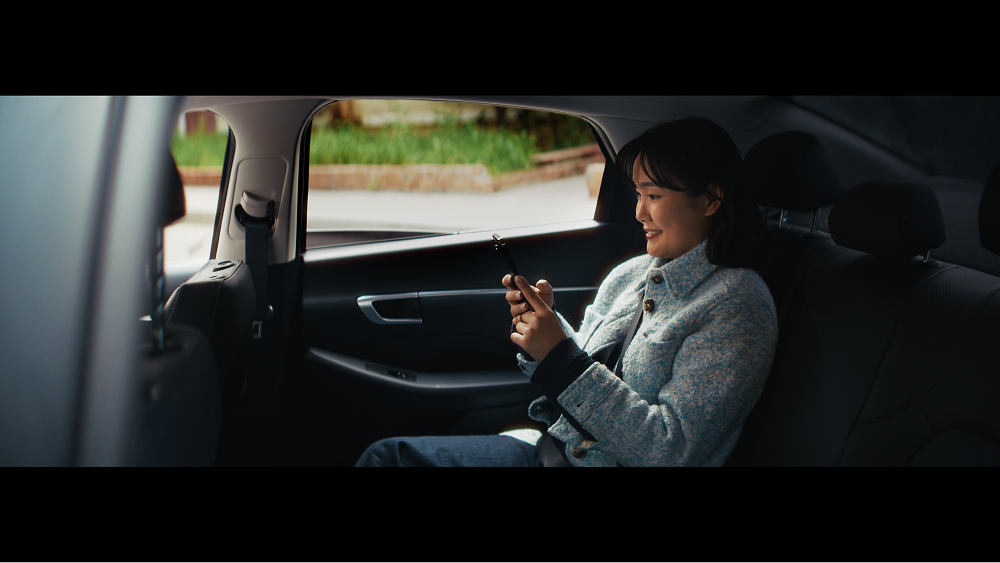 A person sitting in the back seat of a car while using a smartphone
