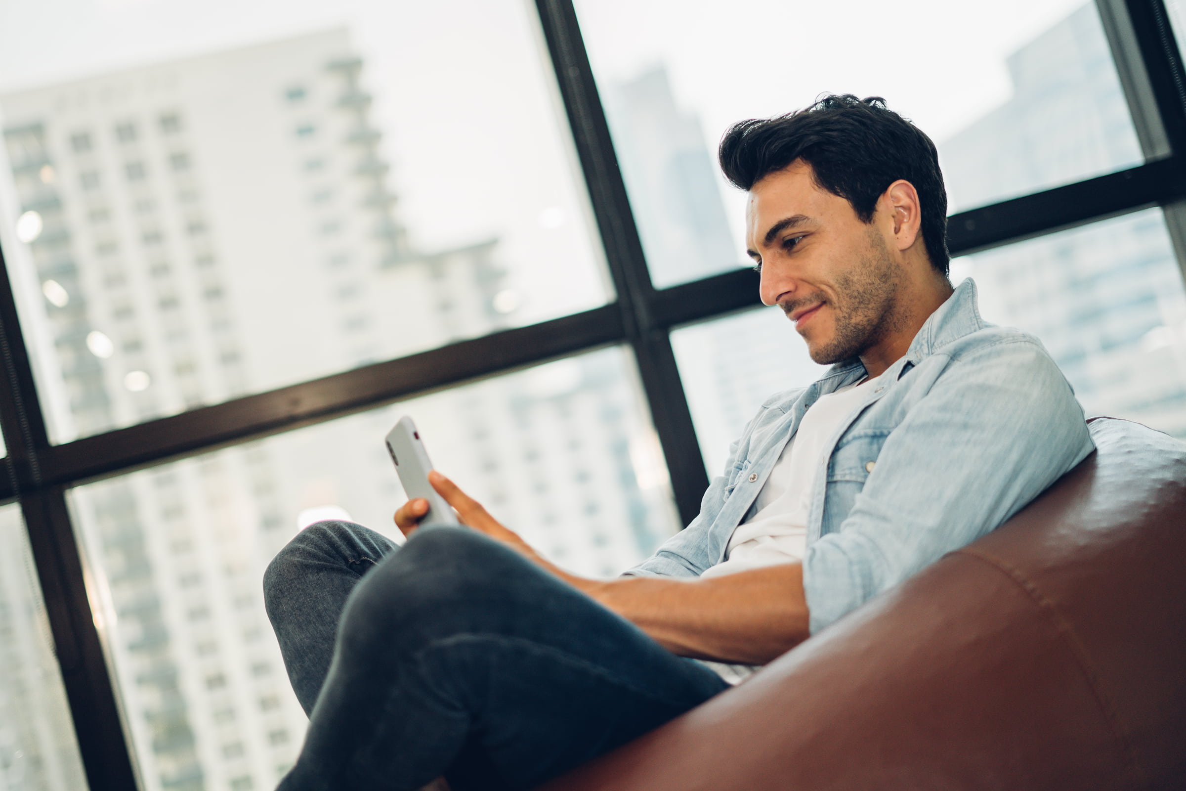 Hombre sentado en un saco de dormir y mirando su móvil