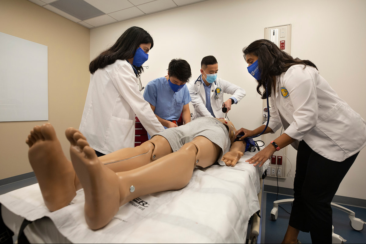 Medical students gathered around a full-body medical training mannequin