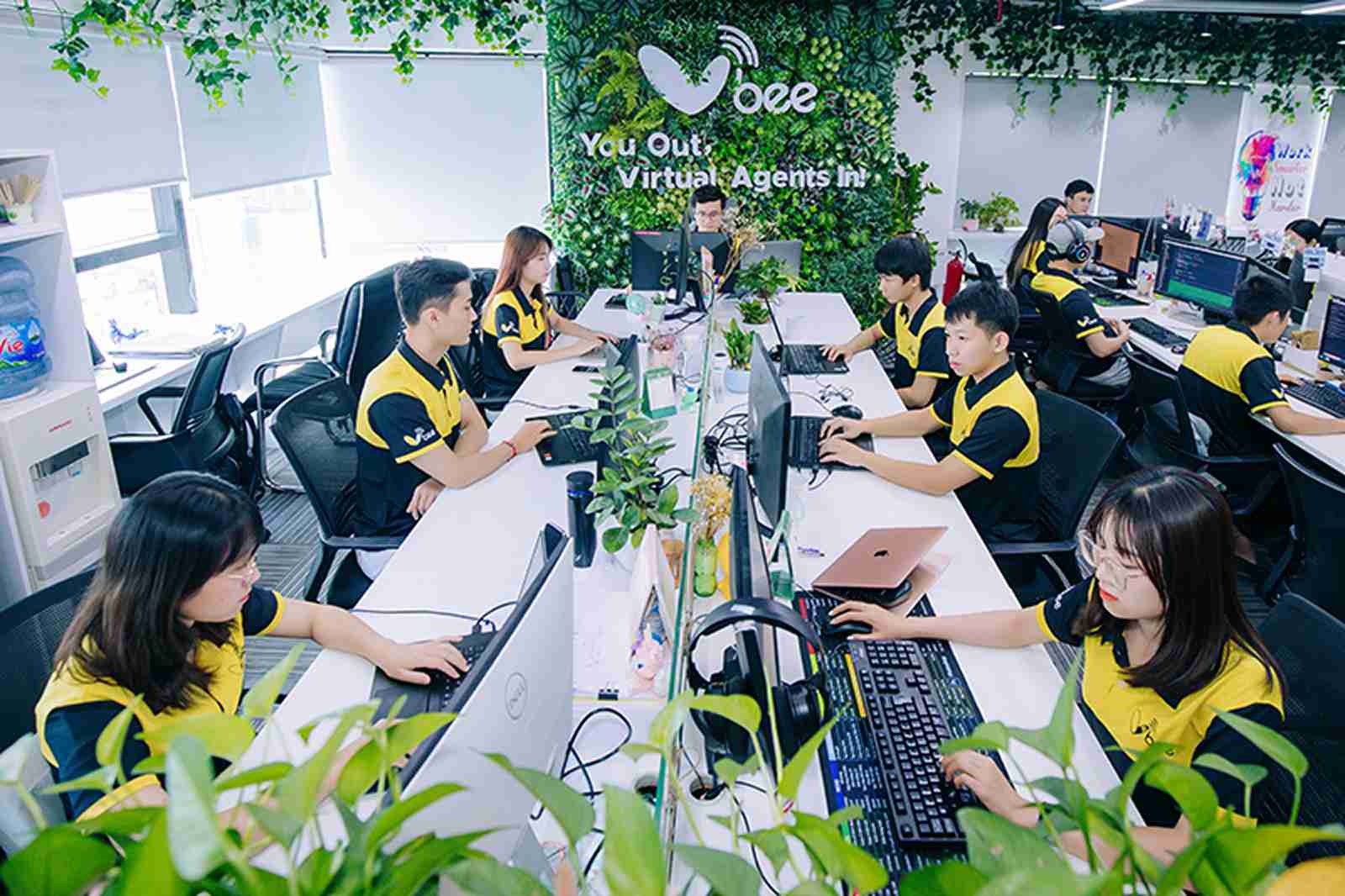 Vbee staff in yellow uniforms working at their desks