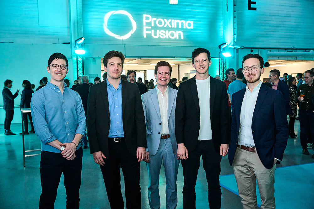 The five co-founders of Proxima Fusion pose together in an industrial event space under a glowing company logo