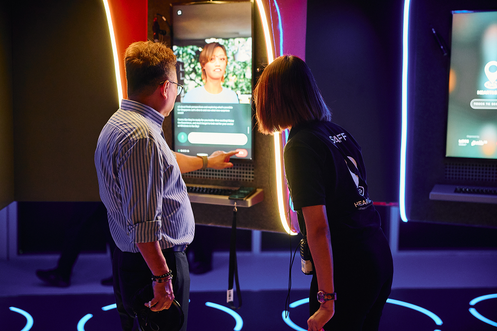 Two people standing in front of a digital kiosk with glowing neon-like accents