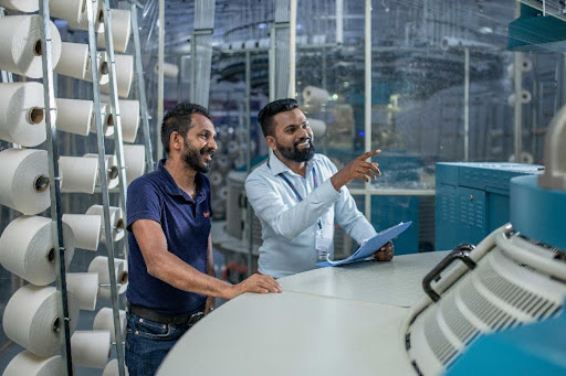 Two men inspecting textile factory machinery