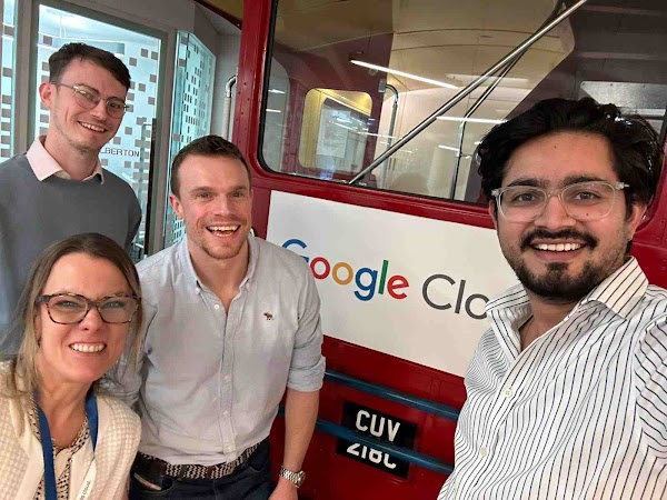 Four individuals smiling with Google Cloud logo in the background