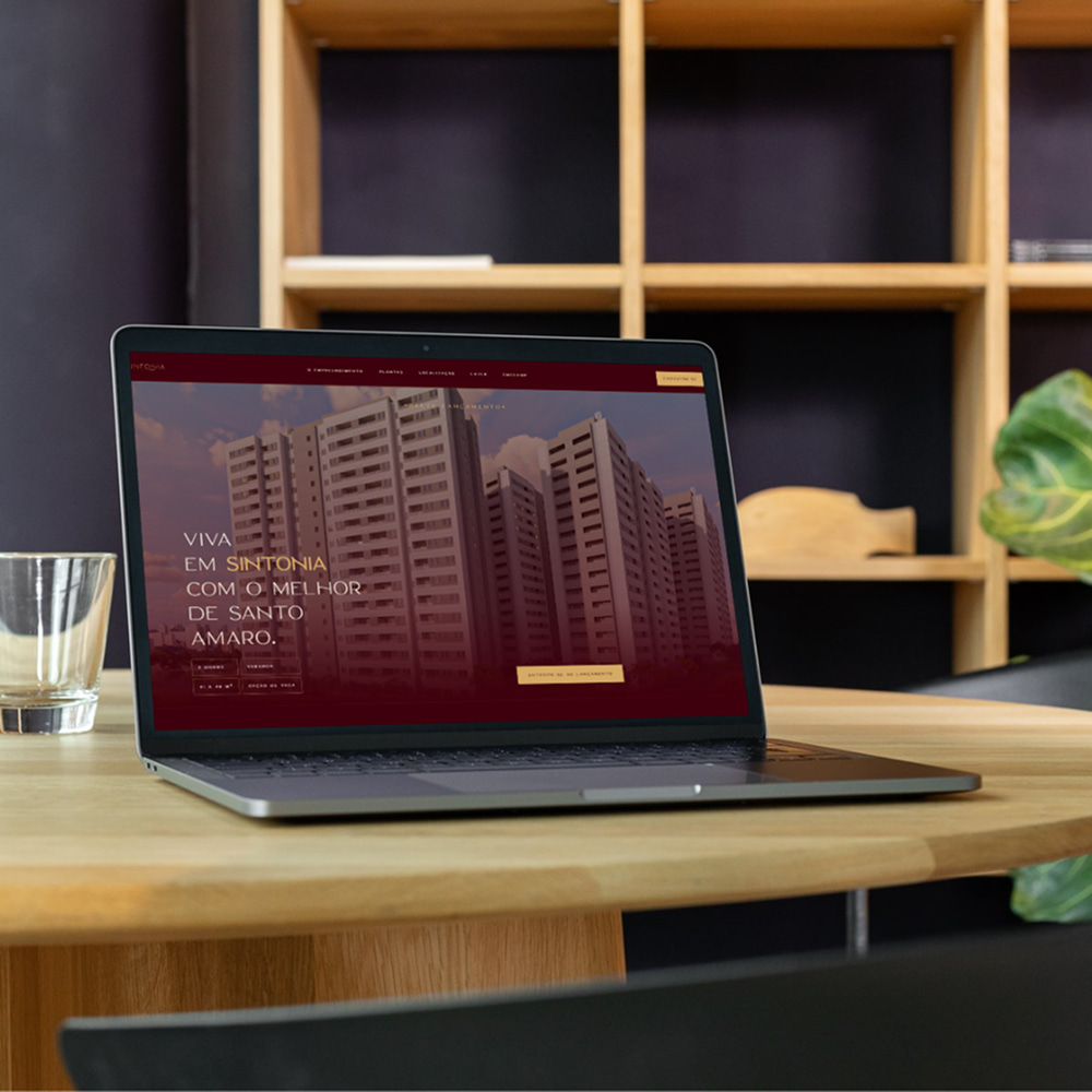 A laptop on a wooden table displays a real estate website in Portuguese featuring high-rise buildings in Santo Amaro