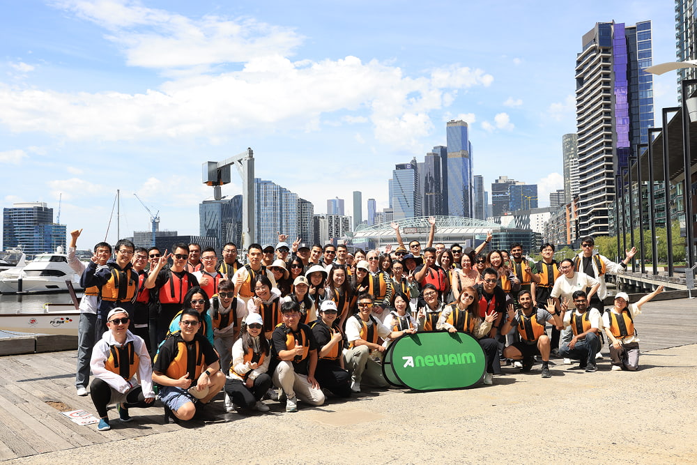 Large group of people in life jackets posing by city harbor
