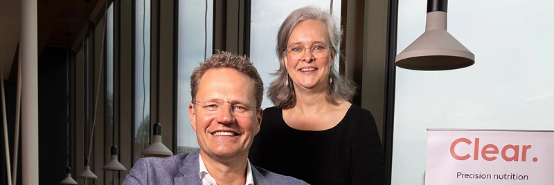 A man and woman smiling with Clear.bio signage in background