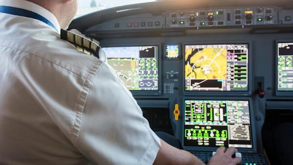 pilot at controls looking at various screens and metrics