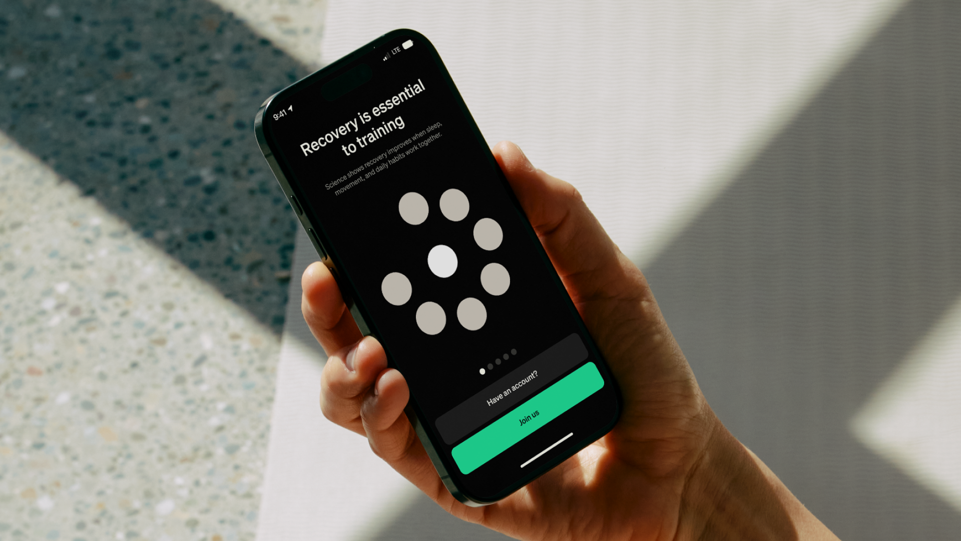 Hand holding a smart phone displaying "Recovery is essential to training"