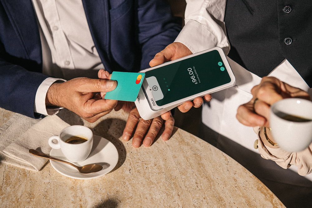 Customer taps card on a handheld payment terminal at a cafe