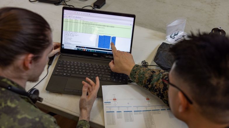 Two service members comparing digital and paper documentation