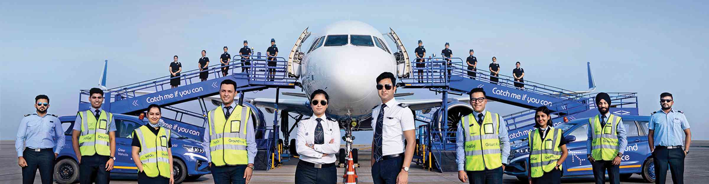 Indigo crew posing against background of aircraft
