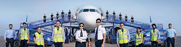 Indigo crew posing against background of aircraft