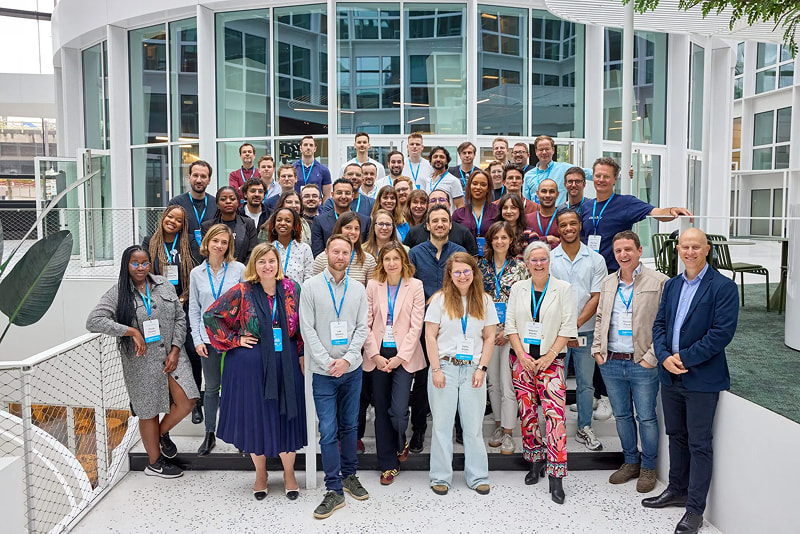 Group photo of a large team inside a modern glass building