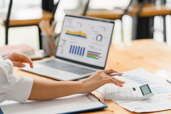 An individual working on a computer and calculator