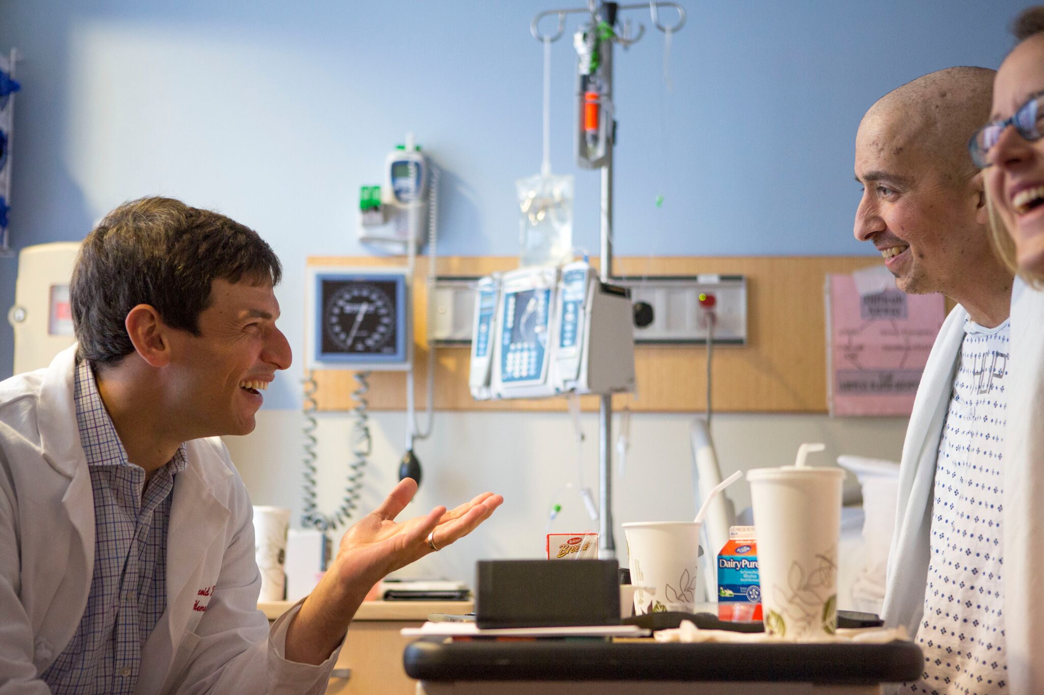 A doctor smiles while talking with two patients in a hospital