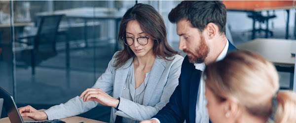 Two women and a man viewing laptop screen