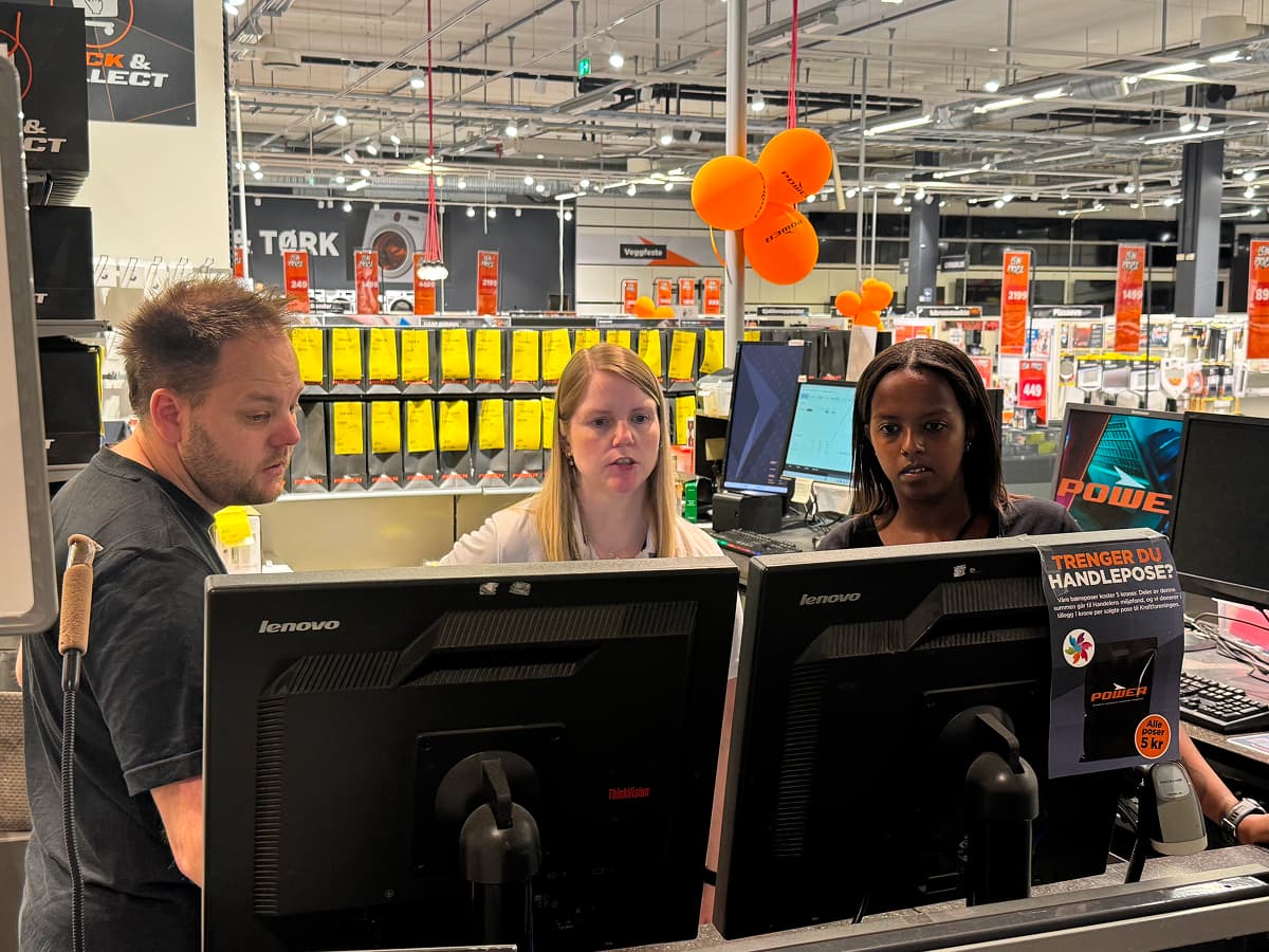 Three people looking at computer screens at a retail store 
