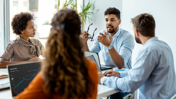 four people at a business meeting with one man talking