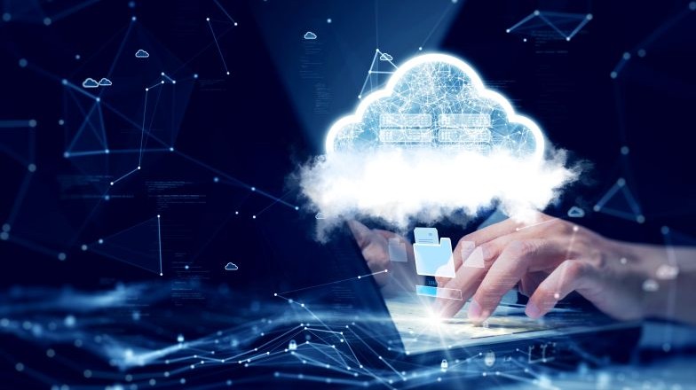 Hands working on a laptop with cloud icon hovering above