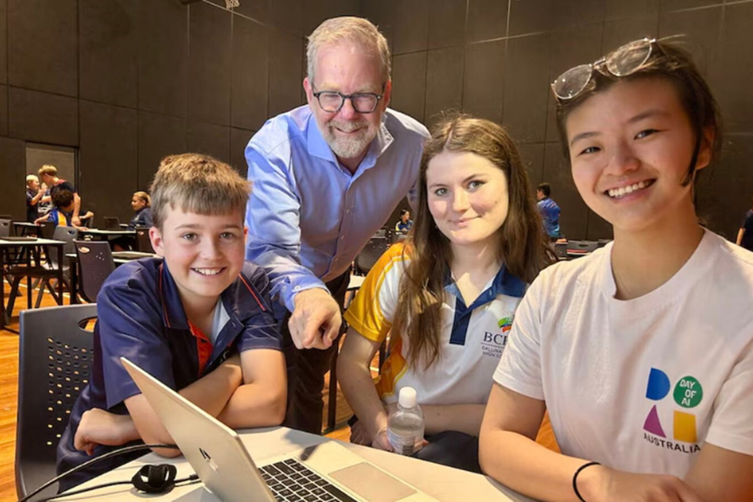 Three students and a teacher posing with a laptop
