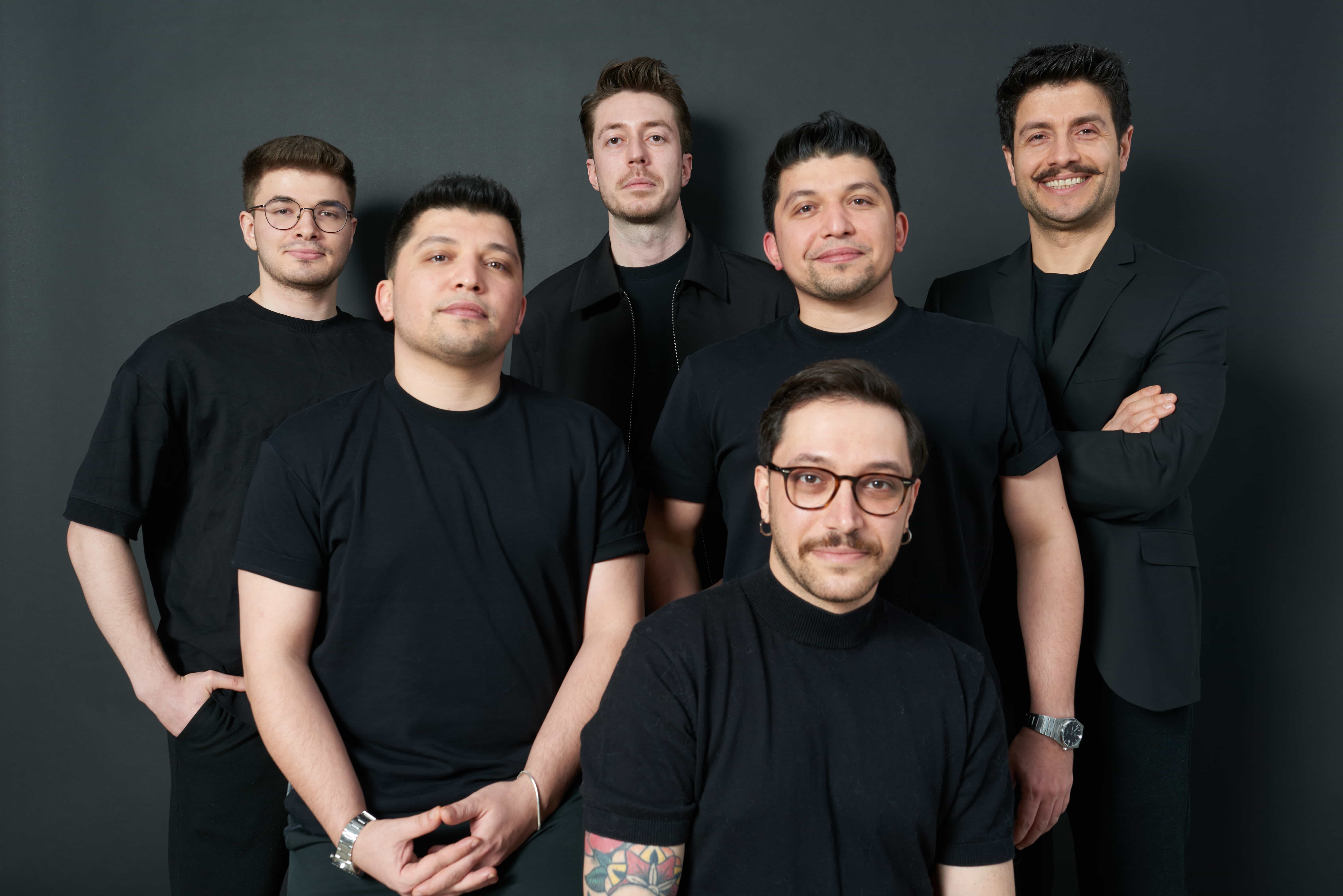 Six men from Replenit, including CEO Ilyas Kurklu and CTO Egemen Akdan, pose in black attire against a dark grey background