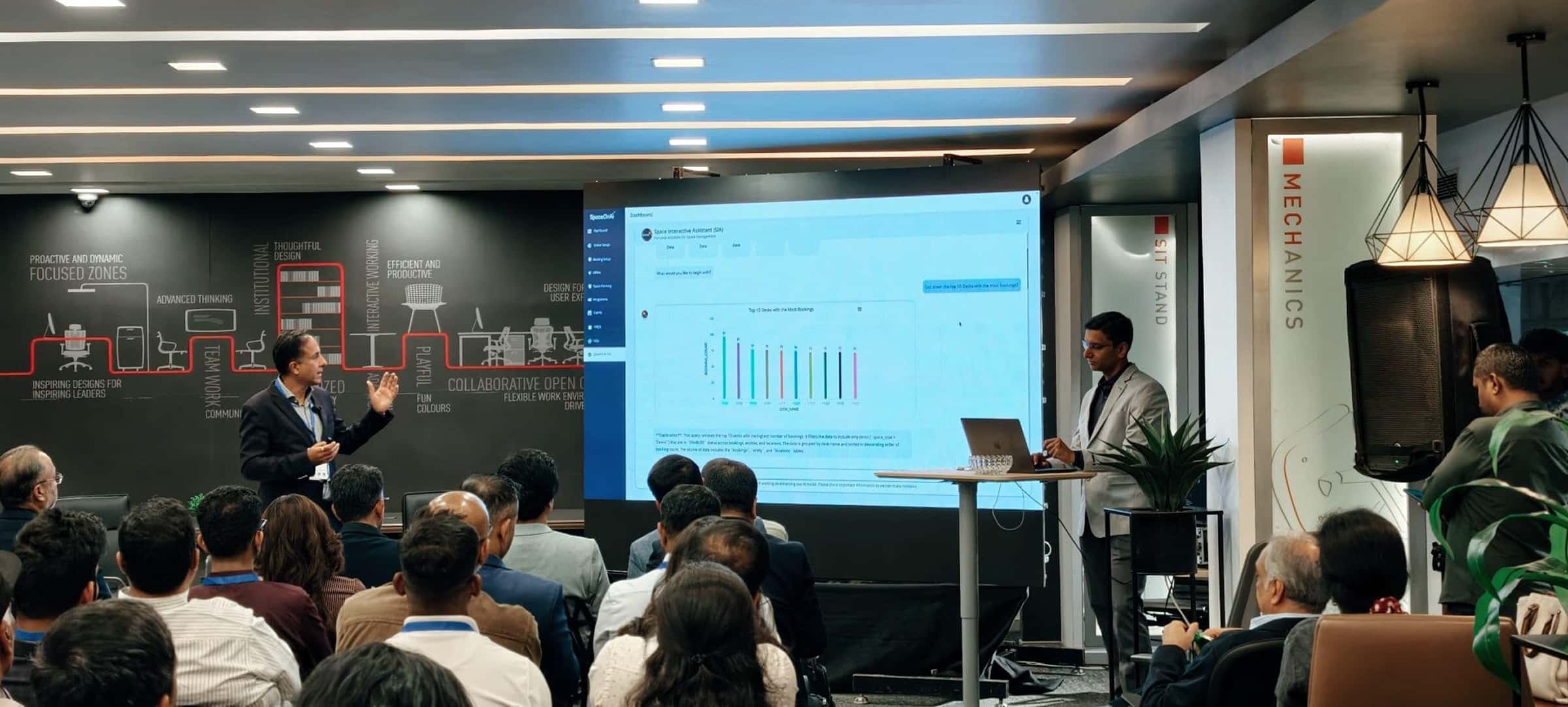Speakers presenting a data dashboard on a large screen