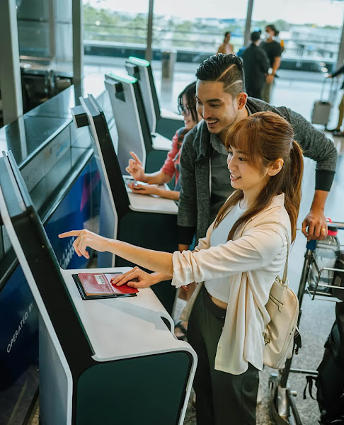 A man and woman looking at a ticketing kiosk