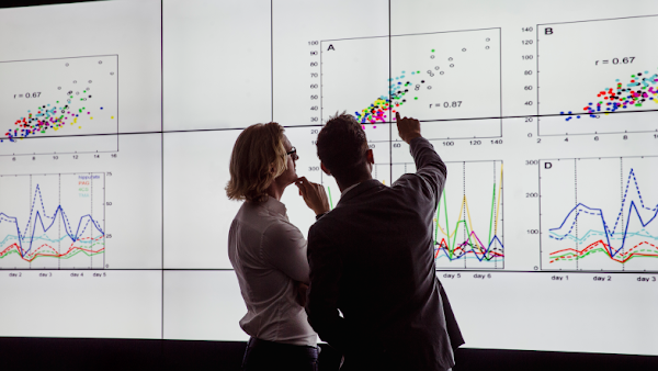 two people reviewing data on a large screen