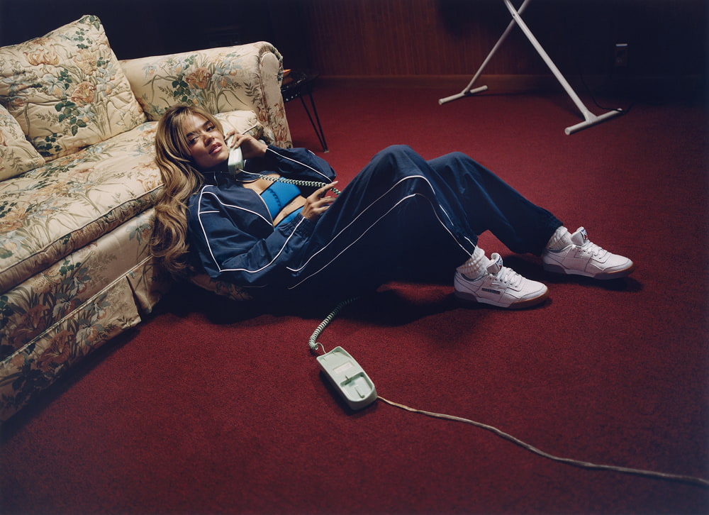 Woman on floor by sofa, talking on phone