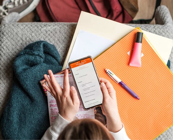 Nomad Education app on a smartphone held by an individual