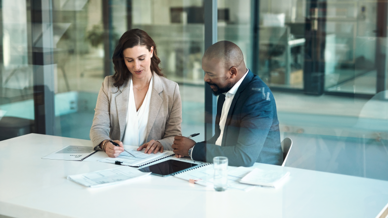 two people working together reviewing documents and a tablet
