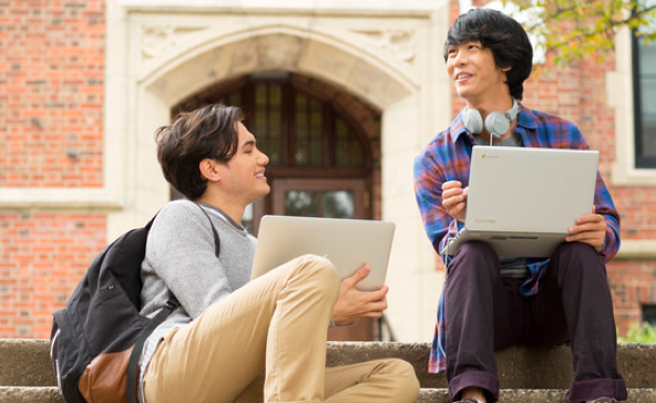 dua siswa sedang mengerjakan tugas di laptop mereka di kampus sekolah