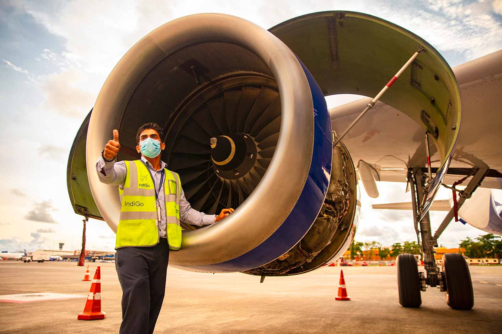 Indigo technician giving a thumbs up standing near the right jet engine
