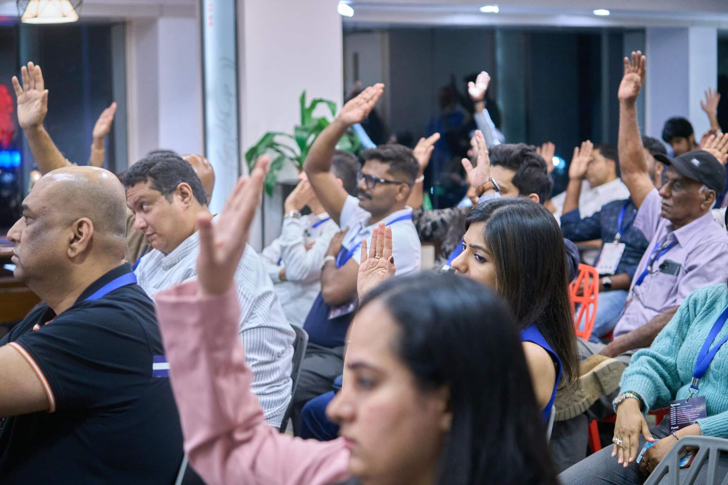 Audience members raising hands at a conference