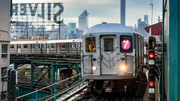 MTA employee in aboveground metro train with city in background