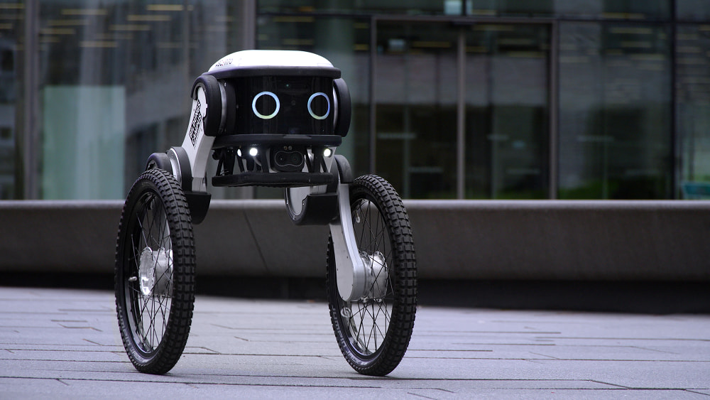 A white and black bipedal robot with large wheels
