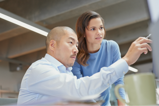 Mann und Frau, die auf einen Bildschirm zeigen