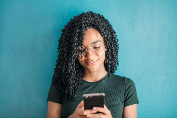 A curly-haired girl looking at her phone