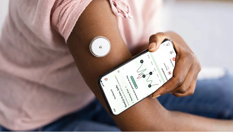 Glucose monitor sensor on an arm with its data on smartphone