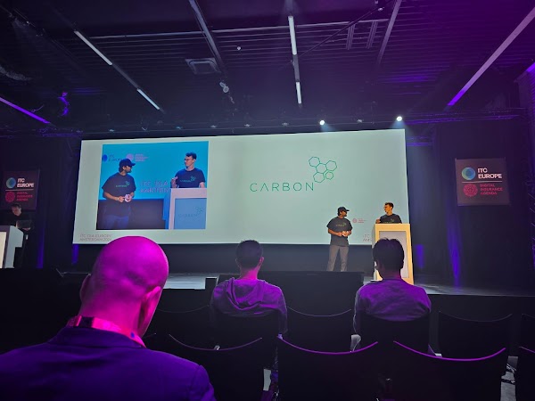 Two individuals shown on stage at a Carbon Underwriting event