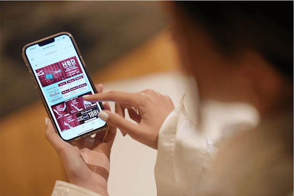 A hand holding a smartphone with Central Retail Group app open on it