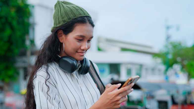 woman wearing hat reviewing phone in a city