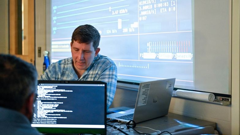 People reviewing code with a large projector screen in the background